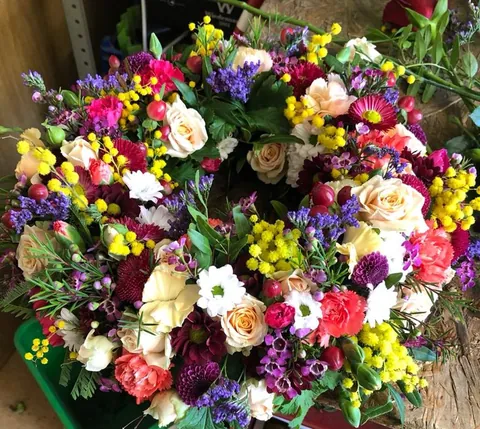 Farbenfrohes Blumenarrangement mit Mimosen, Rosen und Nelken