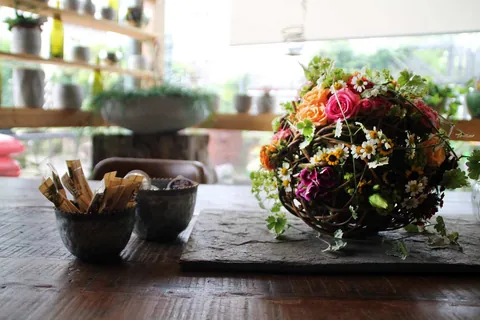 Blumenkugel aus Rosen, Kamille und Weidenzweigen als Tischdekoration