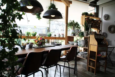Lange Holztafel im Cafeline mit Blumendekoration und Hängeleuchten