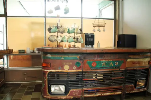 Theke des Cafeline aus einer alten Lkw-Front mit Tassen und Kaffeemaschine